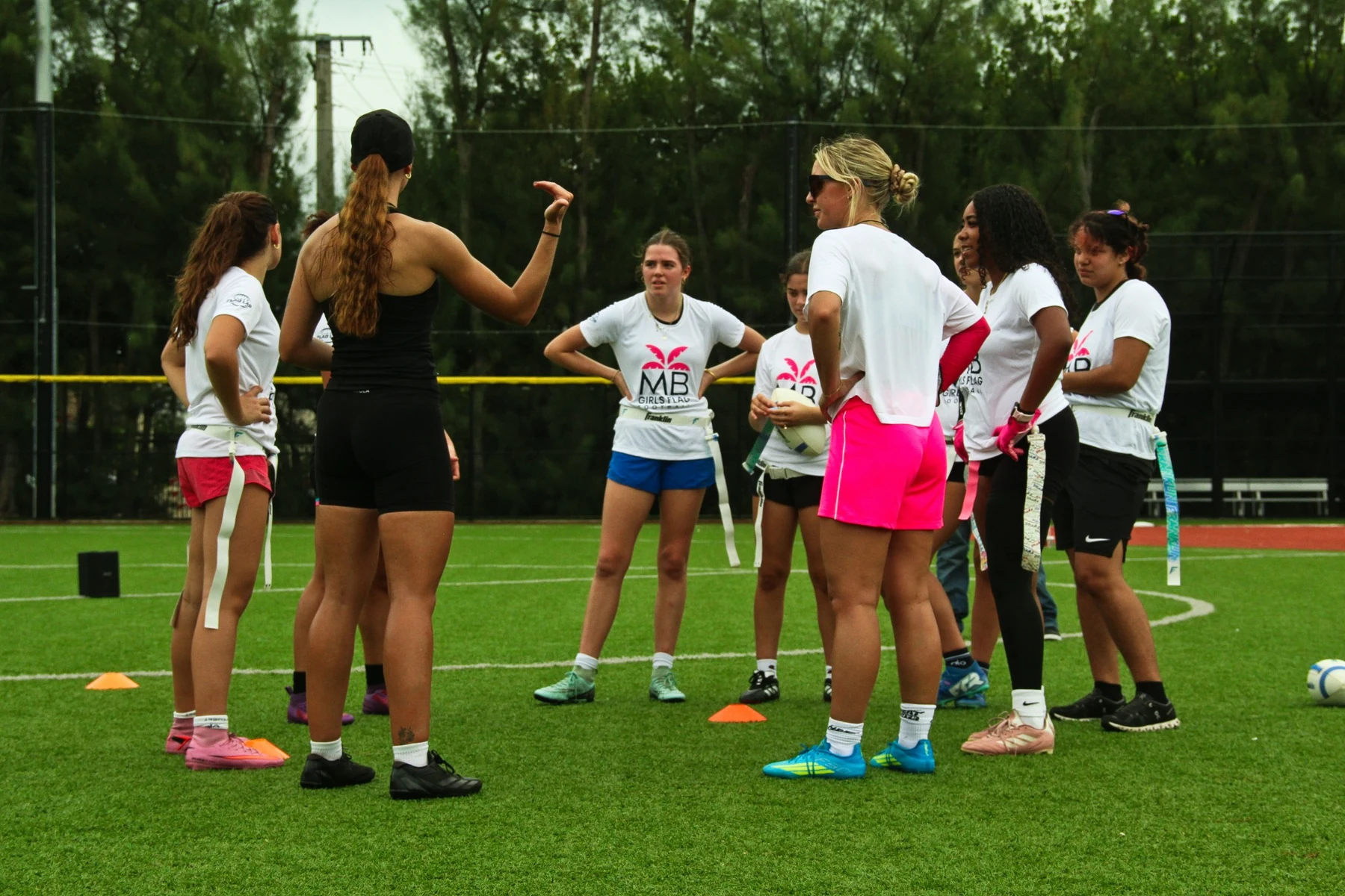 Female coaches leading a group of girls through a flag-football session