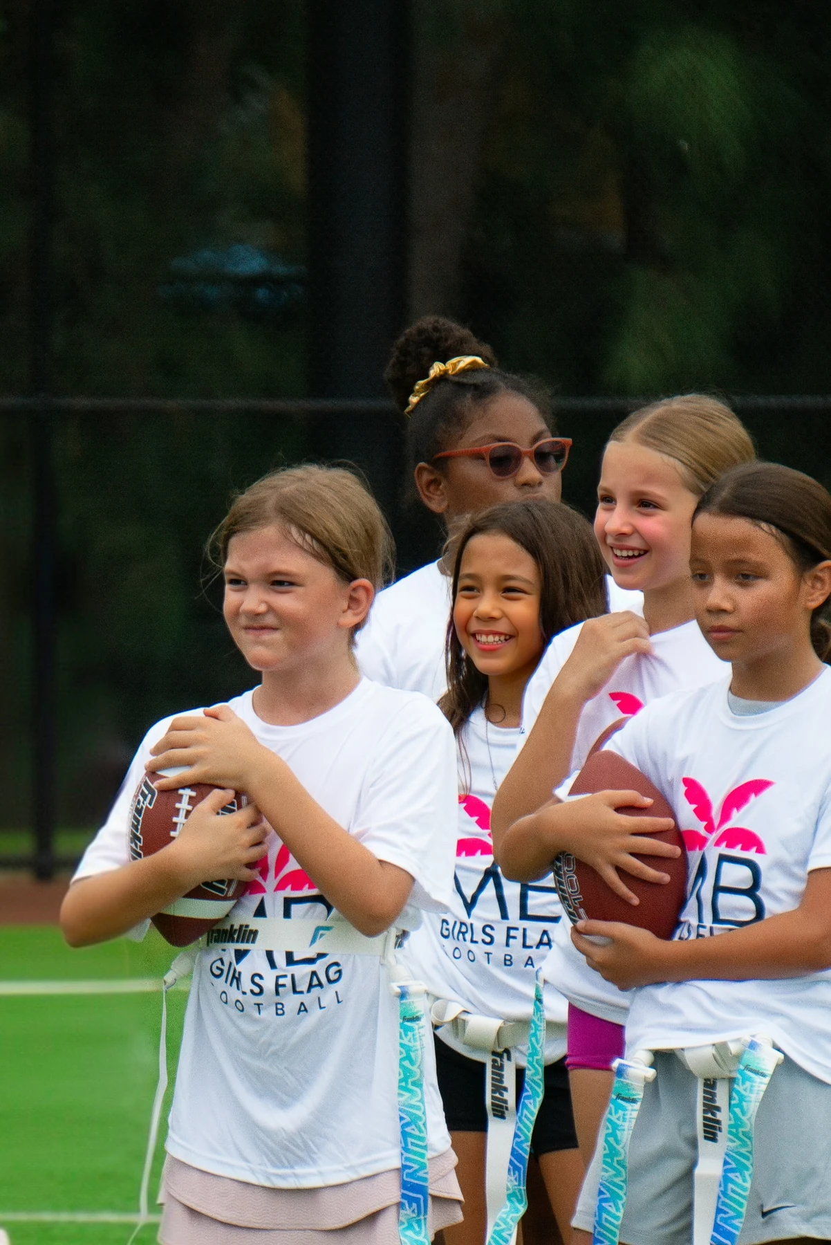 Girls with footballs and flag belts enjoying practice together