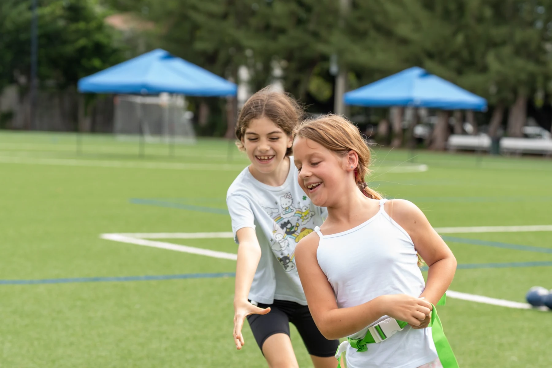 Two girls smiling as they play flag football together