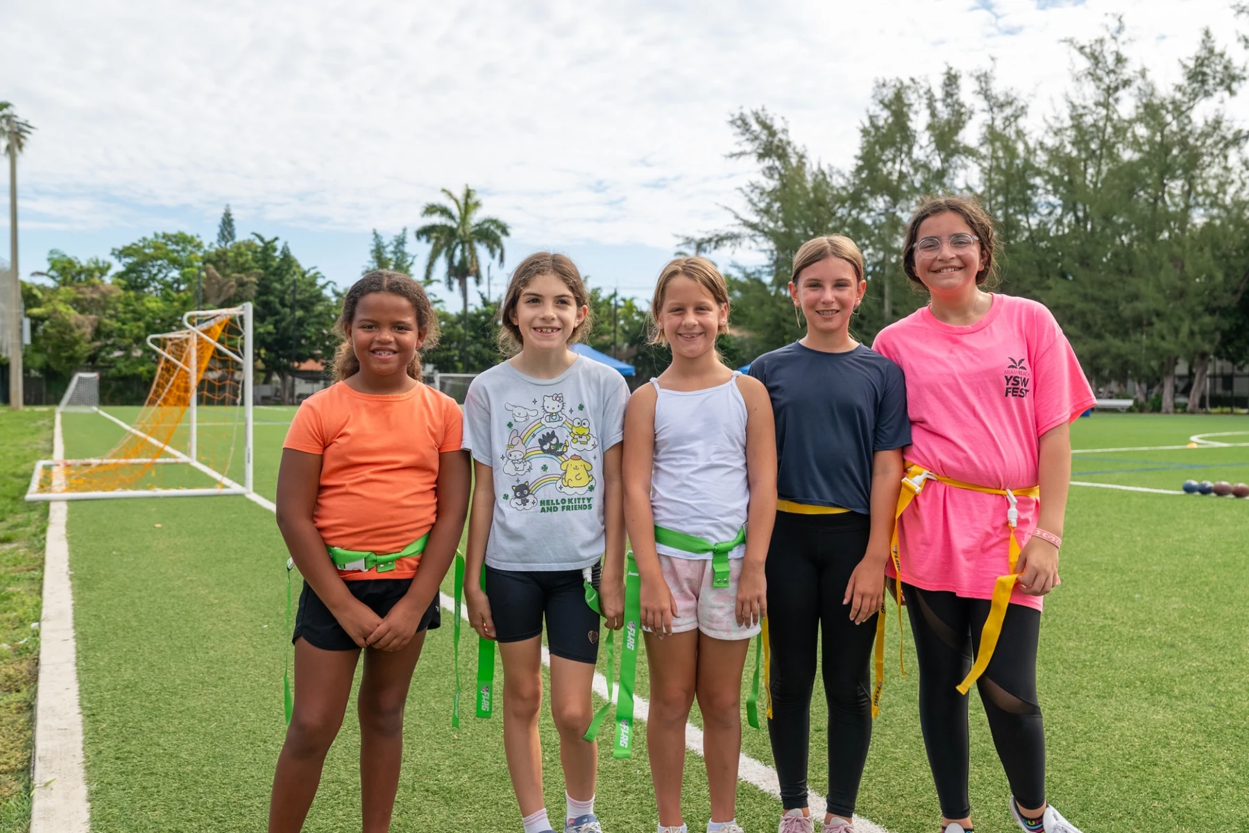 Five girls smiling together on the field after a flag-football activity