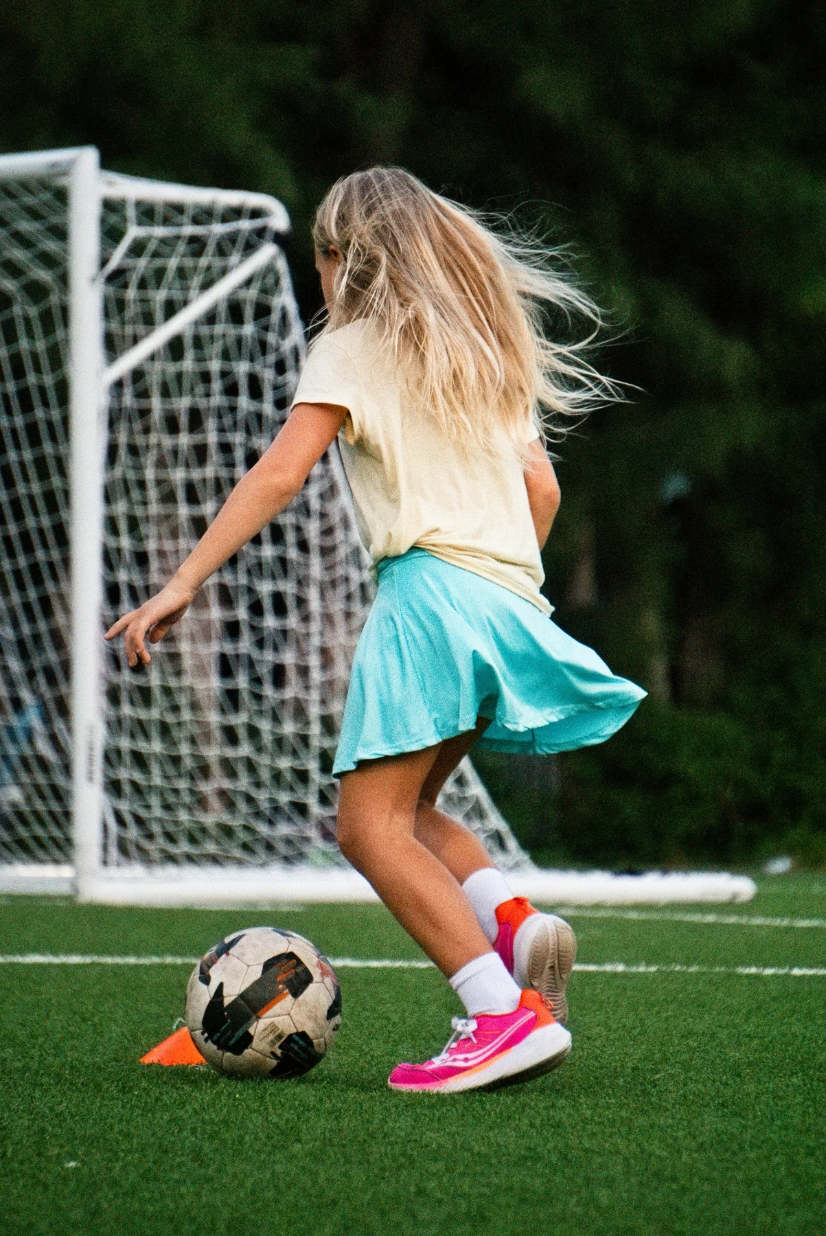 Girl dribbling a soccer ball near the goal