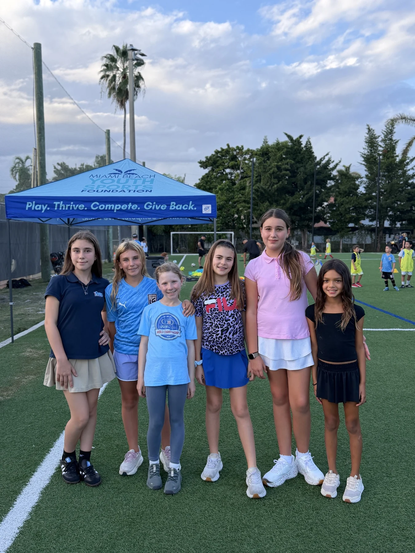 Six girls standing together at a community soccer gathering