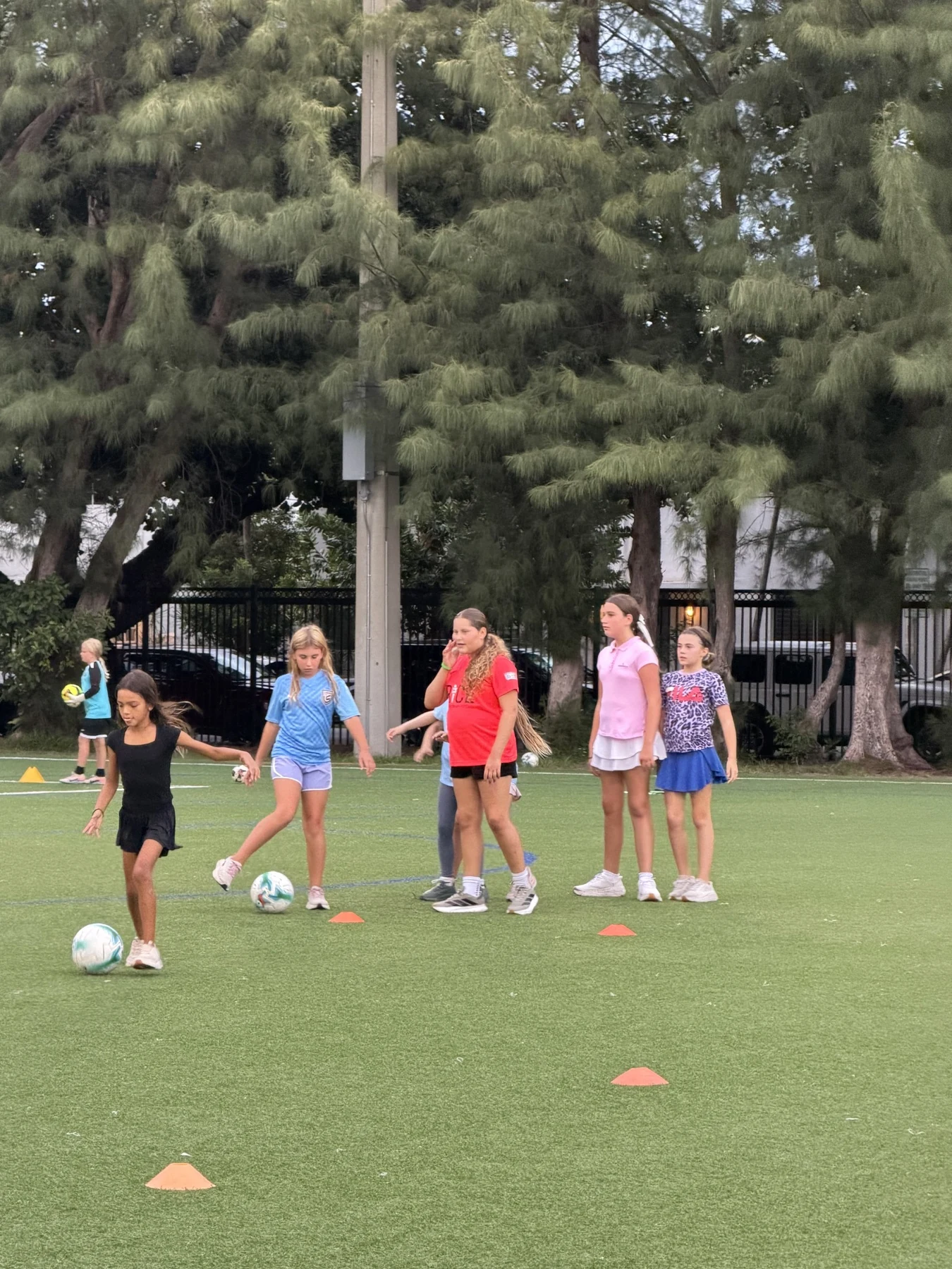 Girls practicing dribbling at an evening community soccer session