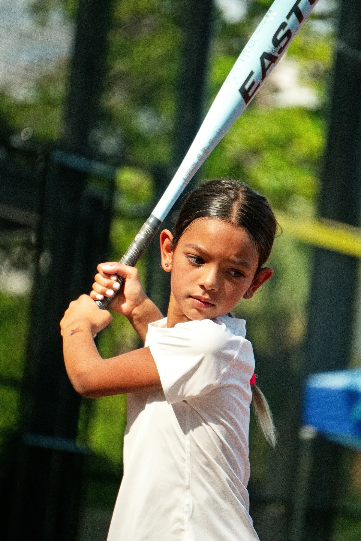 Girl concentrating on her softball batting stance during community practice