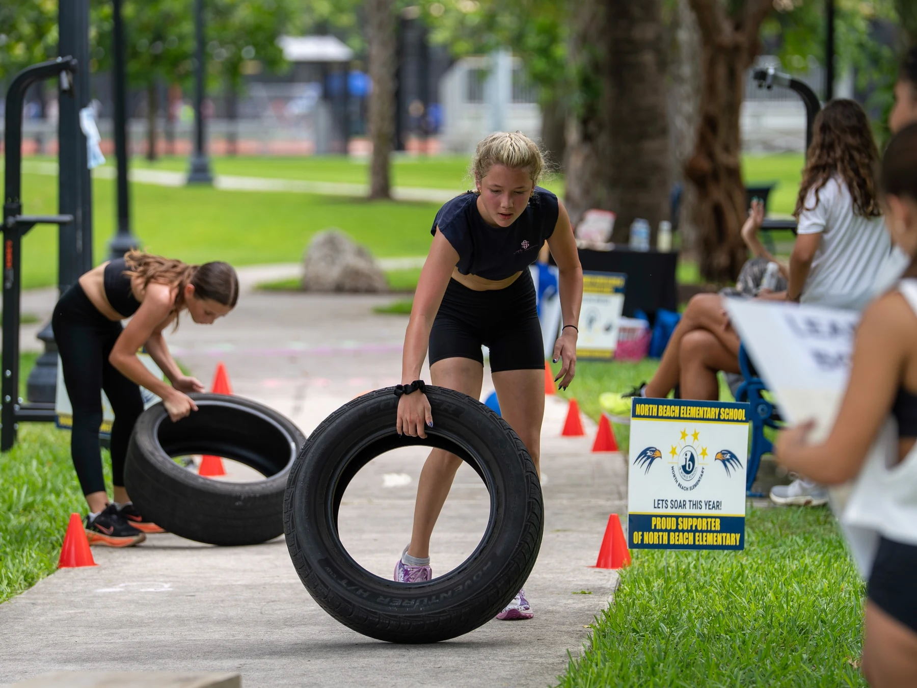 Girls moving tires during an outdoor strength and fitness activity